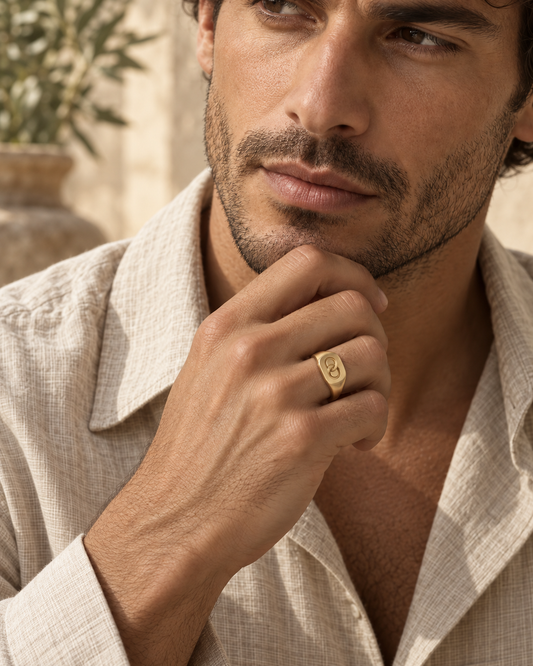 Man in a linen shirt wearing the AEQUORO Small Signet ring in 18k yellow gold