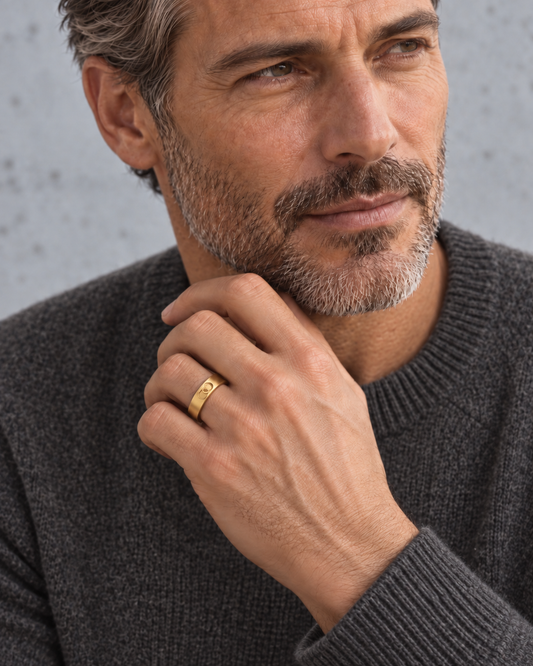 Man in a grey sweater wearing the AEQUORO Narrow Band ring in 18k yellow gold